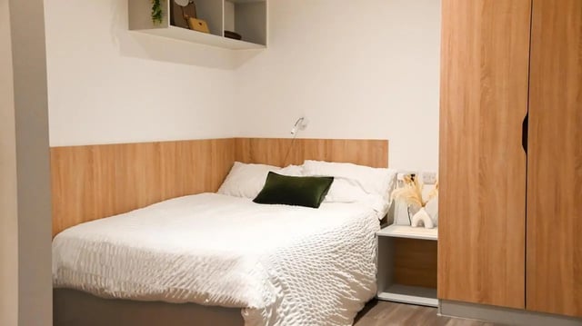 Bed with white bedding dark pillow bedside table and wardrobe bedroom at Hill View Place in Exeter Student Accommodation