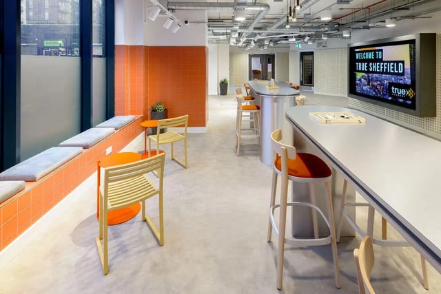 Modern lounge with orange seating and bar stools. at True Sheffield in Sheffield Student Accommodation