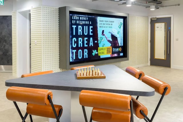 Table with chess set and orange chairs lounge at True Sheffield in Sheffield Student Accommodation