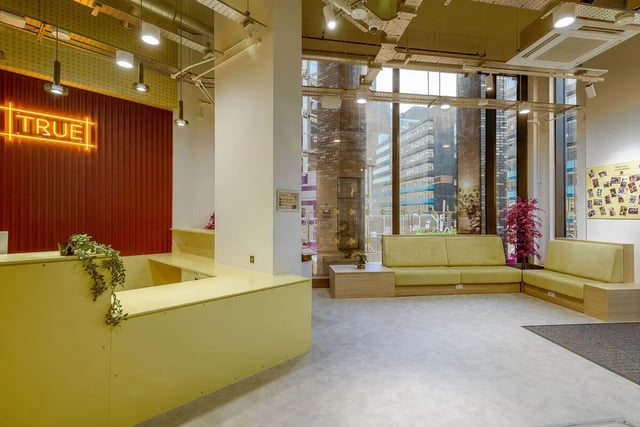 Yellow reception desk neon sign sofas lounge area at True Sheffield in Sheffield Student Accommodation