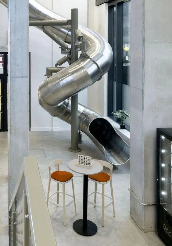 Metal spiral slide with table and chairs recreation area at True Sheffield in Sheffield Student Accommodation