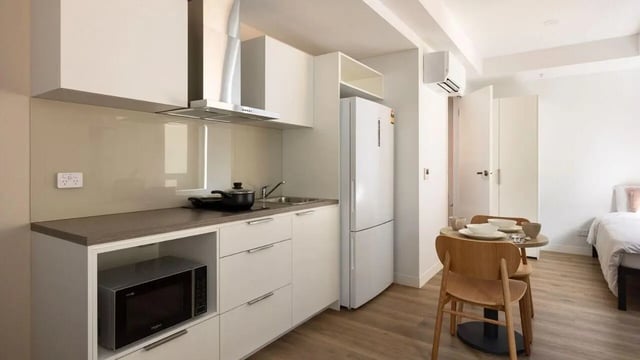 Kitchen with microwave fridge table chairs and bed. at UniLodge Perth Central in Perth Student Accommodation