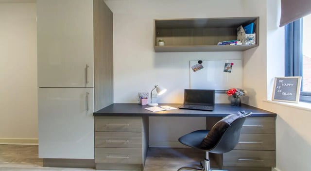 Desk with laptop lamp flowers and cabinets study area at St Giles Studios in Durham Student Accommodation