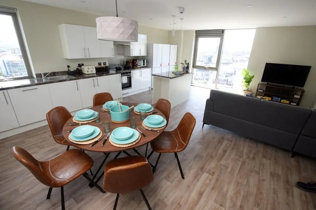 Dining table chairs kitchen sofa television living room at LIV Student Belfast in Belfast Student Accommodation