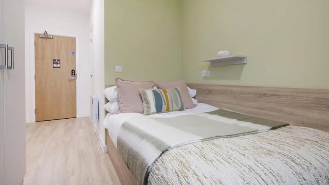 Bed with pillows blankets and a shelf Bedroom at St Gabriels in Manchester Student Accommodation
