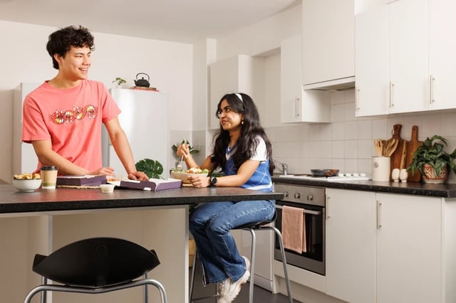 Couple eating pizza and salad kitchen area at Shrubhill House in Edinburgh Student Accommodation