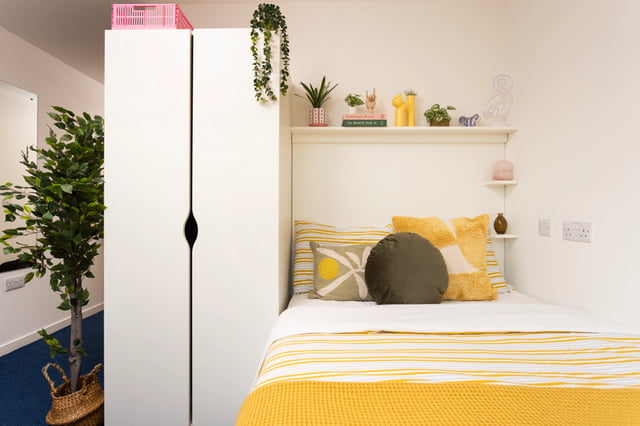 Bed with yellow striped bedding white wardrobe bedroom at Shrubhill House in Edinburgh Student Accommodation
