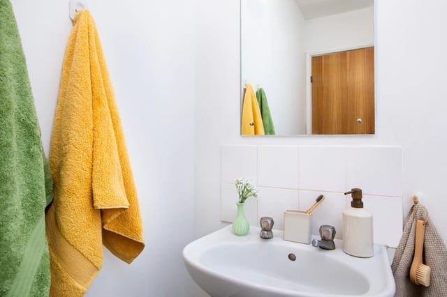 Sink with towels toothbrush soap dispenser bathroom at Ewen Henderson Court in London Student Accommodation