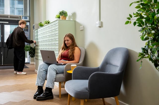 Mailboxes woman with laptop chairs lounge area at Trafalgar Hall in Portsmouth Student Accommodation