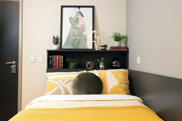 Bed with yellow blanket art shelf bedroom at Arch View House in London Student Accommodation