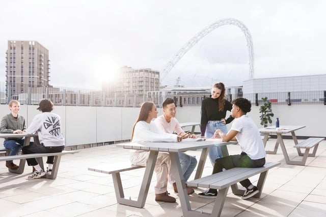 Students talking at picnic tables outdoor study area at Arch View House in London Student Accommodation