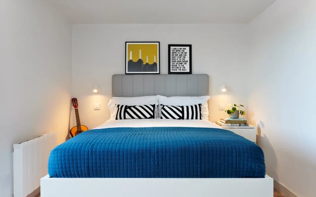 Bed with blue quilt guitar artwork bedroom at Student Castle Durham in Durham Student Accommodation