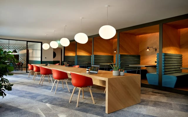 Long communal desk with red chairs and booths study area at Student Castle Durham in Durham Student Accommodation