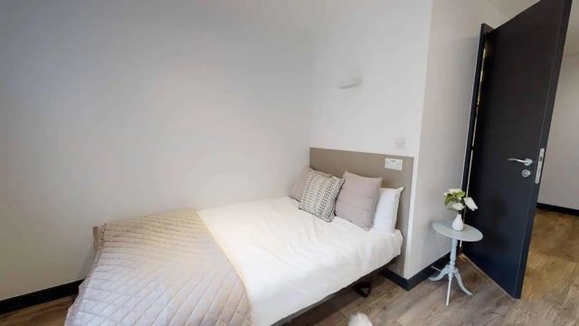 Bed with pillows and a small table bedroom at Opto village in Luton Student Accommodation