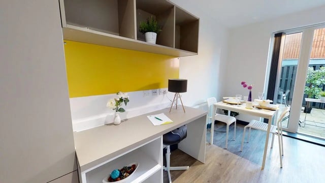 Desk plant flowers table chairs dining area at Opto village in Luton Student Accommodation