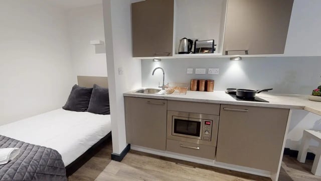 Bed with grey pillows microwave and kitchen kitchen at Opto village in Luton Student Accommodation