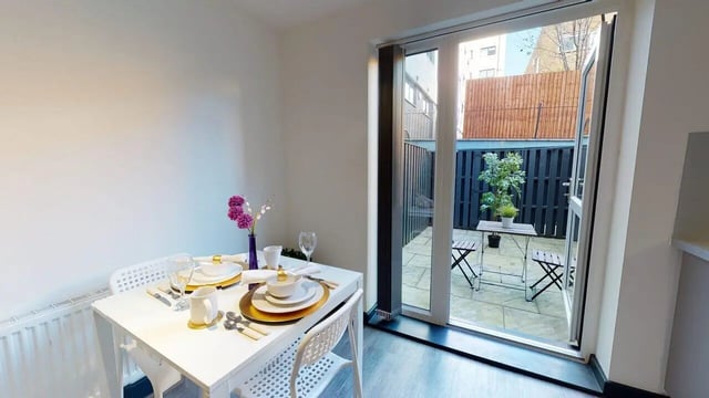 Dining table with place settings leading to patio area exterior at Opto village in Luton Student Accommodation