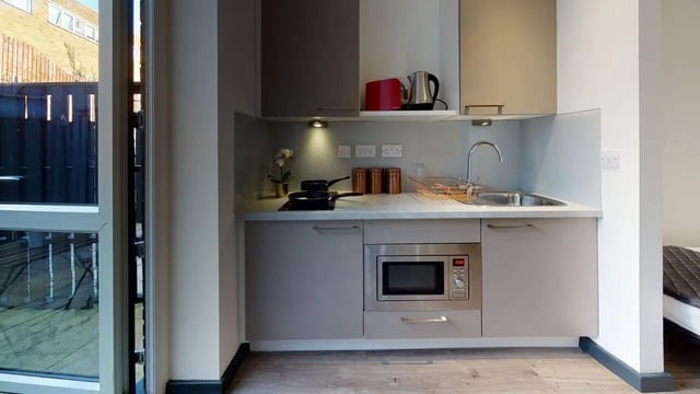 Modern kitchen with microwave sink kettle and pots kitchen at Opto village in Luton Student Accommodation