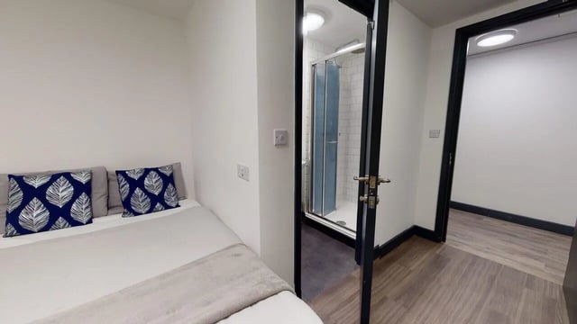 Bed with blue leaf pillows and ensuite shower room bedroom at Chapel Street - Luton in Luton Student Accommodation