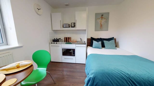 Bed kitchen table and green chair studio apartment at Park House in Luton Student Accommodation