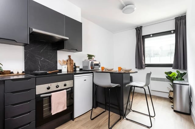 Dark cabinets oven microwave small fridge breakfast bar kitchen at Rosalind Franklin Halls in Portsmouth Student Accommodation