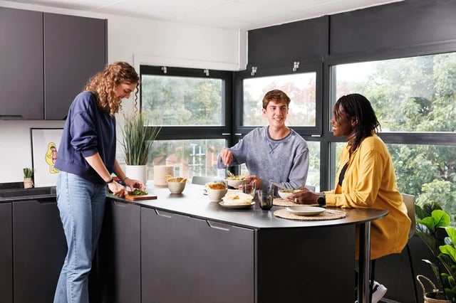 Students eating meal at kitchen island with windows living room at Rosalind Franklin Halls in Portsmouth Student Accommodation
