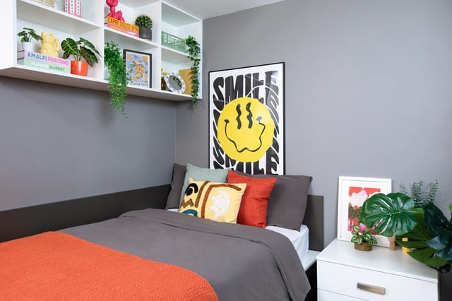 Bed with orange throw cushions and smile poster bedroom at Margaret Rule Hall in Portsmouth Student Accommodation