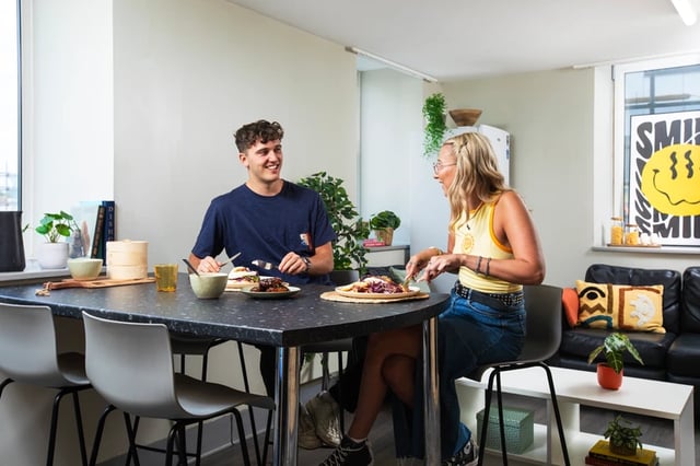 Couple eating at table with plates and chairs living room at Margaret Rule Hall in Portsmouth Student Accommodation