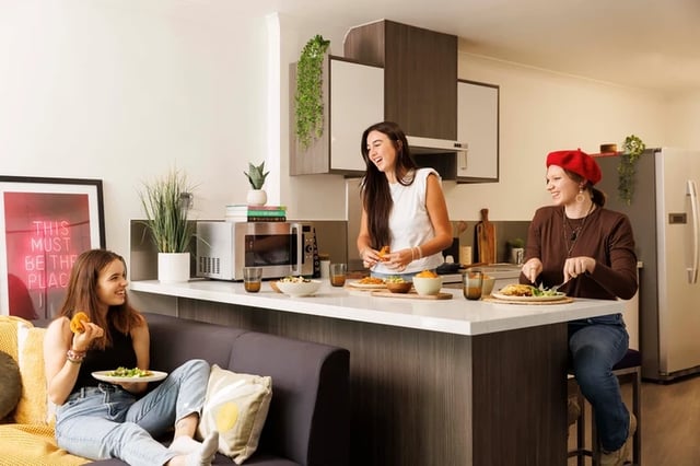 Students eating in kitchen living area at Mill Point in Manchester Student Accommodation