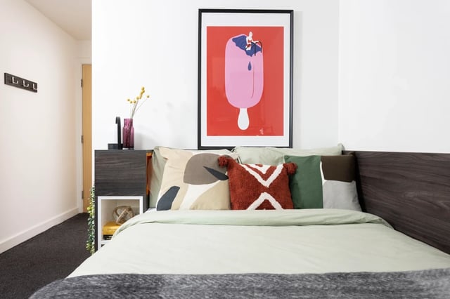 Bed with patterned pillows art and bedside table bedroom at Mill Point in Manchester Student Accommodation