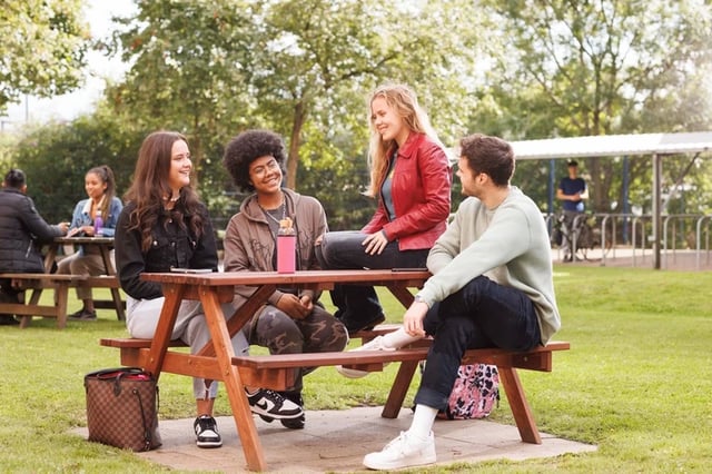 Students relaxing at picnic table outdoor living area at Mill Point in Manchester Student Accommodation