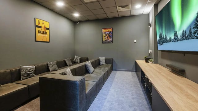 Sofa with pillows large TV wooden cabinet cinema room at St Gabriels in Manchester Student Accommodation