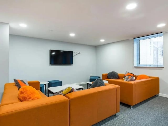 Orange sofas television and blue ottomans living room at Mary Parker House in Plymouth Student Accommodation