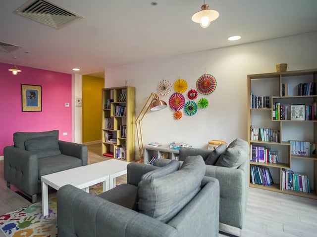 Gray sofas white table colorful wall decor bookshelves lounge at The Recording Rooms in Birmingham Student Accommodation