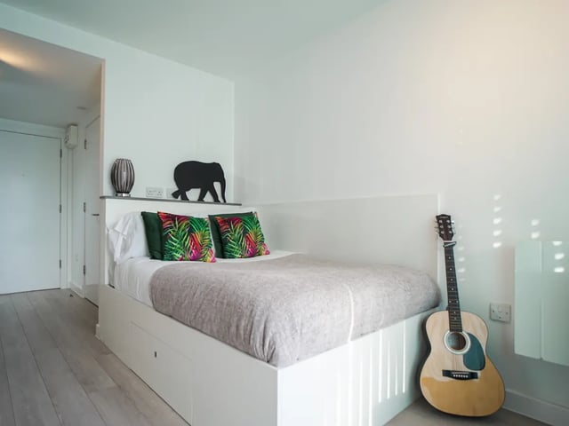 Bed with patterned pillows and guitar bedroom at The Recording Rooms in Birmingham Student Accommodation