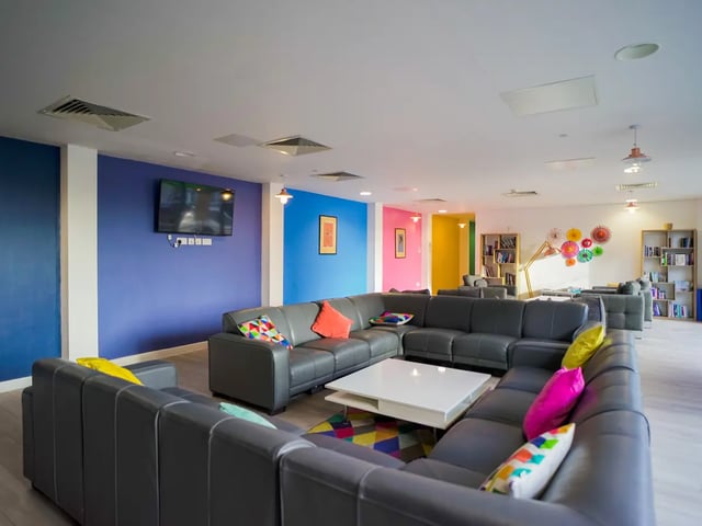 Large grey sectional couch white table colorful pillows living room at The Recording Rooms in Birmingham Student Accommodation