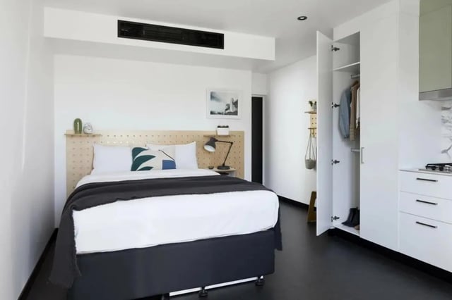 Bed with pillows blanket and open wardrobe bedroom at UKO Paddington Village in Sydney Student Accommodation
