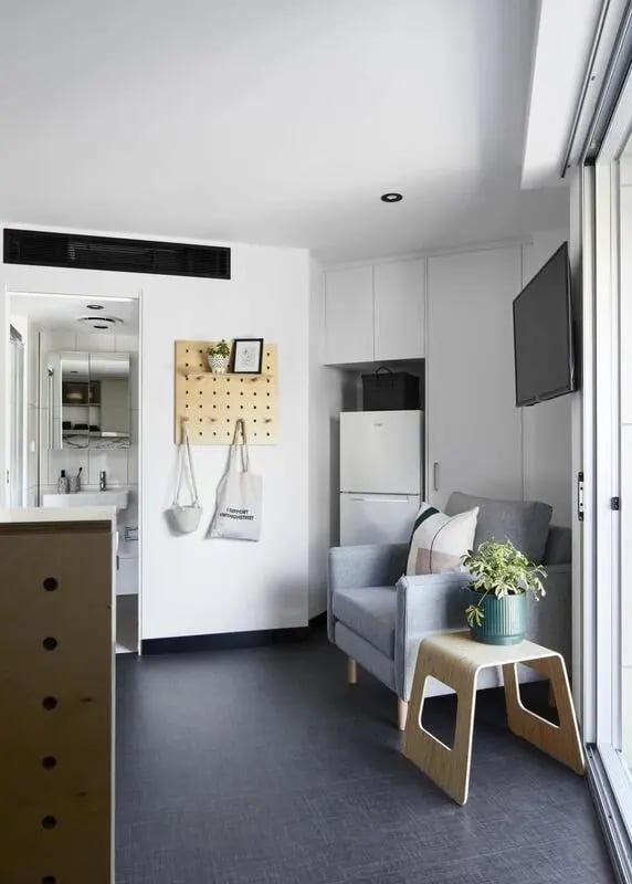 Gray armchair pegboard fridge television living room at UKO Paddington Village in Sydney Student Accommodation