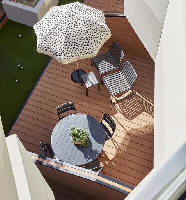 Round table chairs umbrella on wooden deck exterior at UKO Paddington Village in Sydney Student Accommodation
