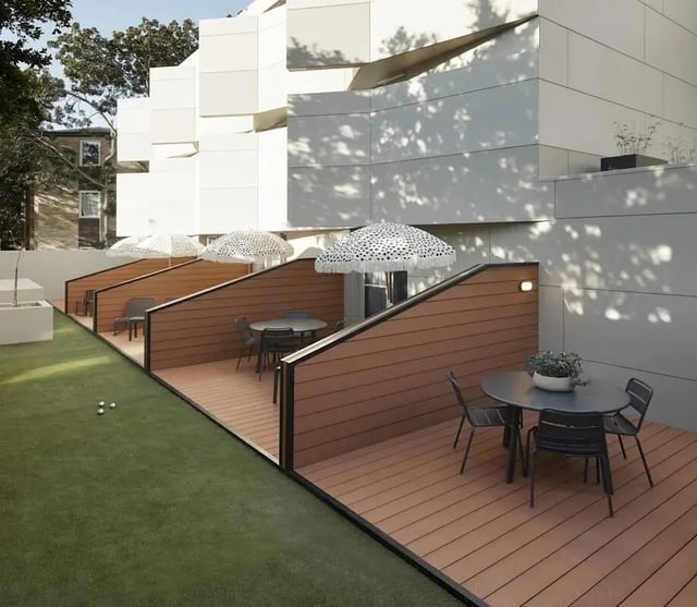 Tables chairs umbrellas on wooden decks exterior at UKO Paddington Village in Sydney Student Accommodation