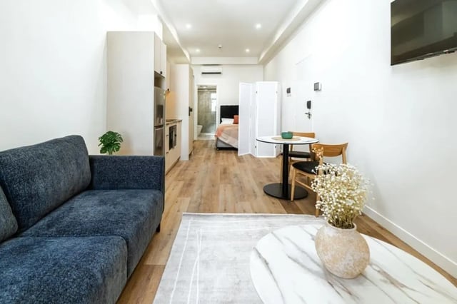 Dark sofa dining table with chairs bedroom kitchen living room at UKO Annandale Tower C in Sydney Student Accommodation