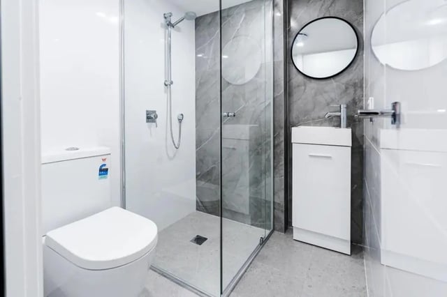 Modern white toilet glass shower grey tiles bathroom at UKO Annandale Tower C in Sydney Student Accommodation