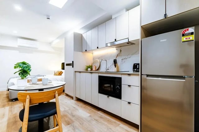 Modern kitchen with stainless steel fridge and dining table kitchen at UKO Annandale Tower C in Sydney Student Accommodation