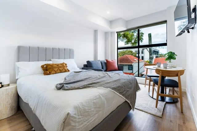 Bed sofa table and chairs bedroom at UKO Annandale Tower C in Sydney Student Accommodation