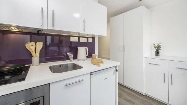 White kitchen cabinets sink kettle wooden utensils kitchen at The Cube Ealing in London Student Accommodation