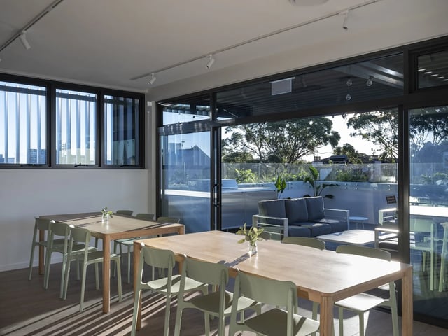 Dining tables chairs windows patio lounge area common room at UKO Glebe in Sydney Student Accommodation