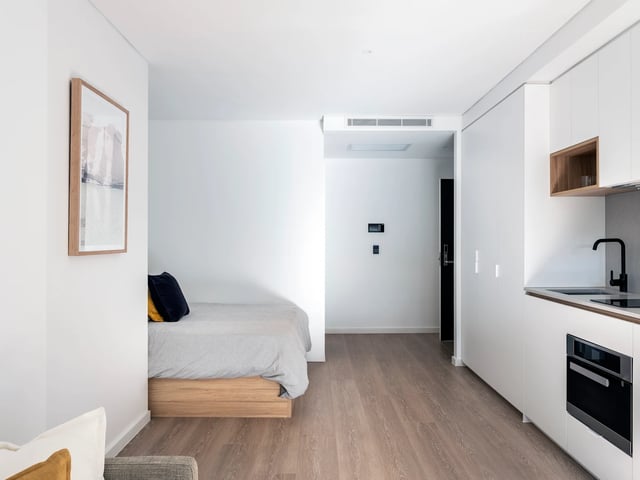 Bed with pillows artwork kitchen area studio apartment at UKO Glebe in Sydney Student Accommodation