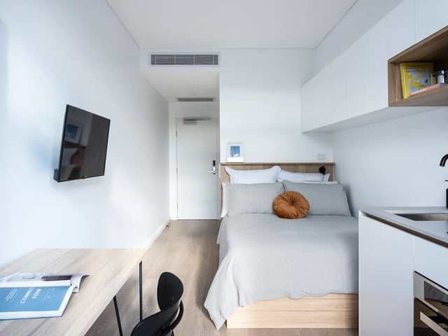 Bed with orange pillow desk TV bedroom at UKO Glebe in Sydney Student Accommodation