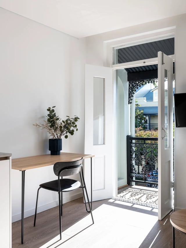 Desk with chair plants and doorway to balcony study area at UKO Glebe in Sydney Student Accommodation