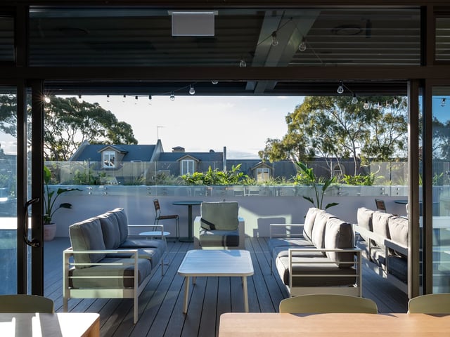 Sofa tables chairs plants and houses exterior living room at UKO Glebe in Sydney Student Accommodation